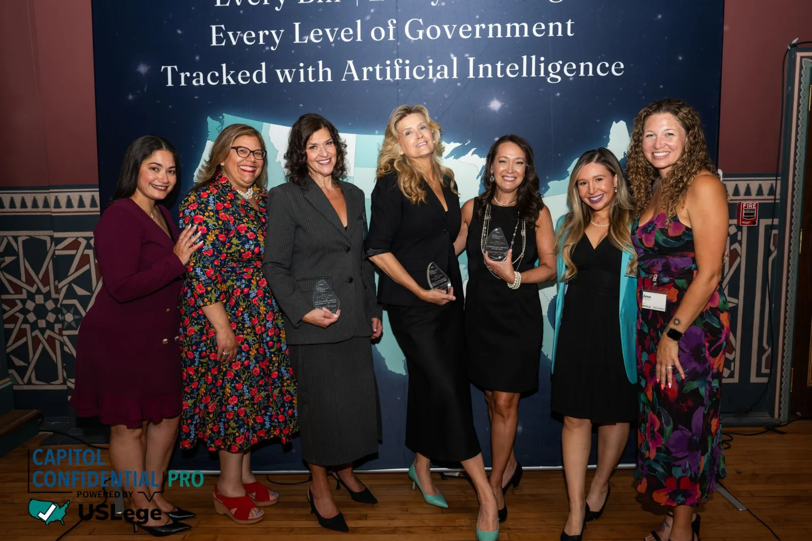A group of honorees holding their engraved crystal awards in front of the USLege backdrop at the 2026 Best in Government Affairs New York awards ceremony