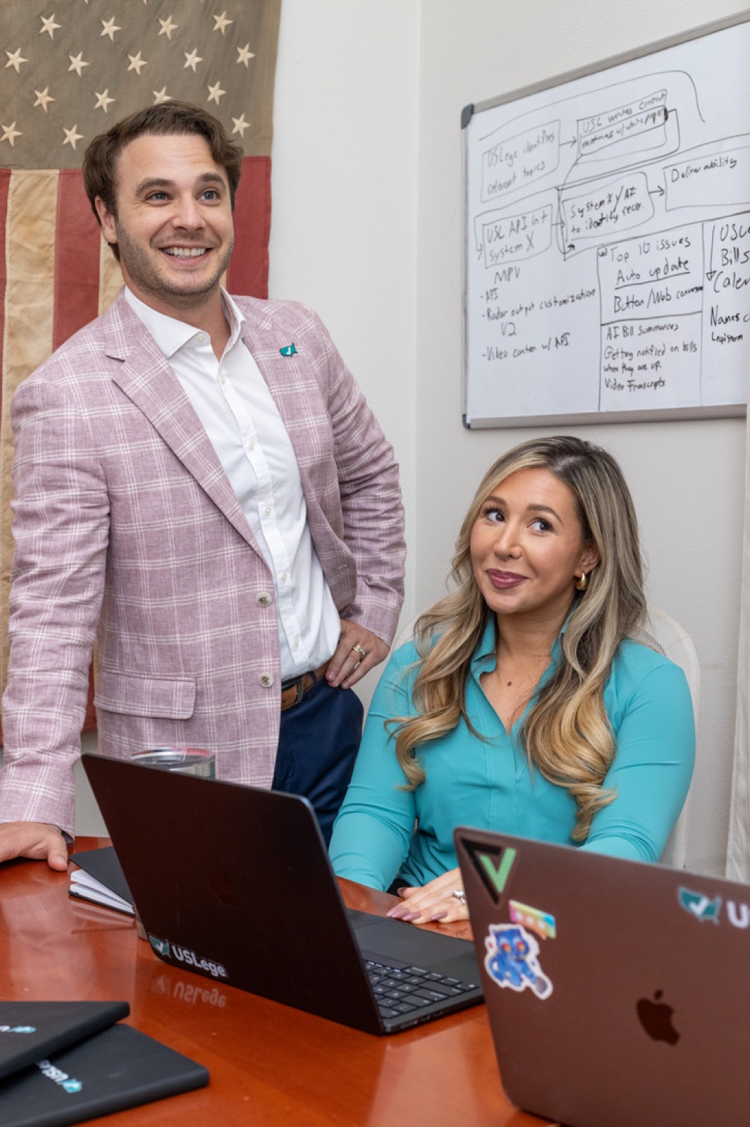 Los cofundadores de USLege Eric y Laura Davis trabajando en un escritorio bajo una bandera estadounidense