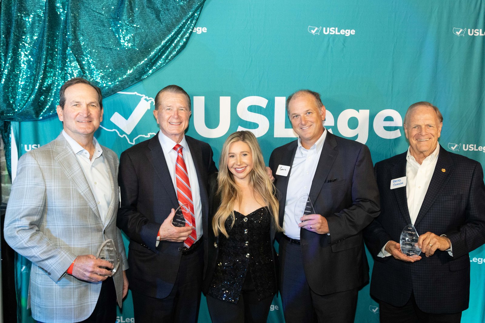 Laura Davis posing with five Lobby Legend award winners in front of the USLege step-and-repeat backdrop