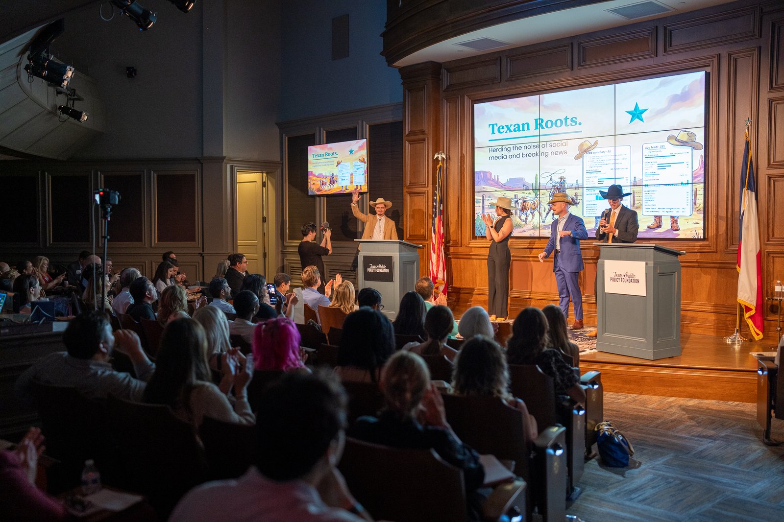 A team presenting their 'Texan Roots' pitch on stage at the Texas Hackathon