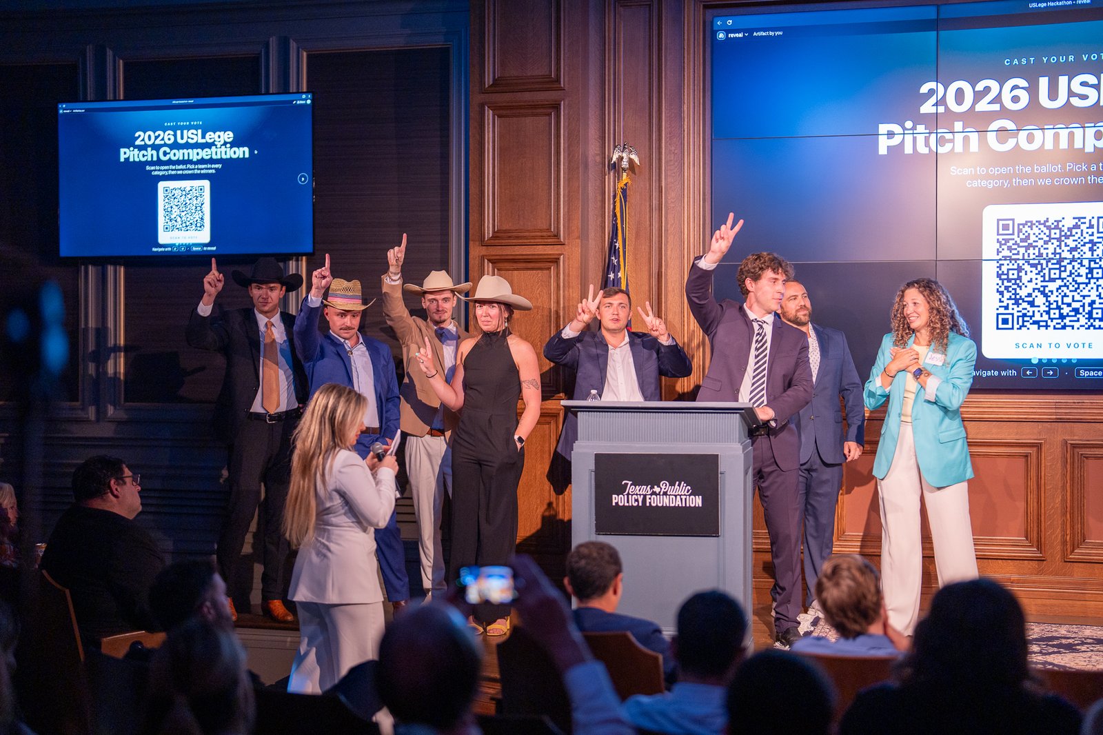 A team in cowboy hats celebrating on stage during the 2026 USLege Pitch Competition