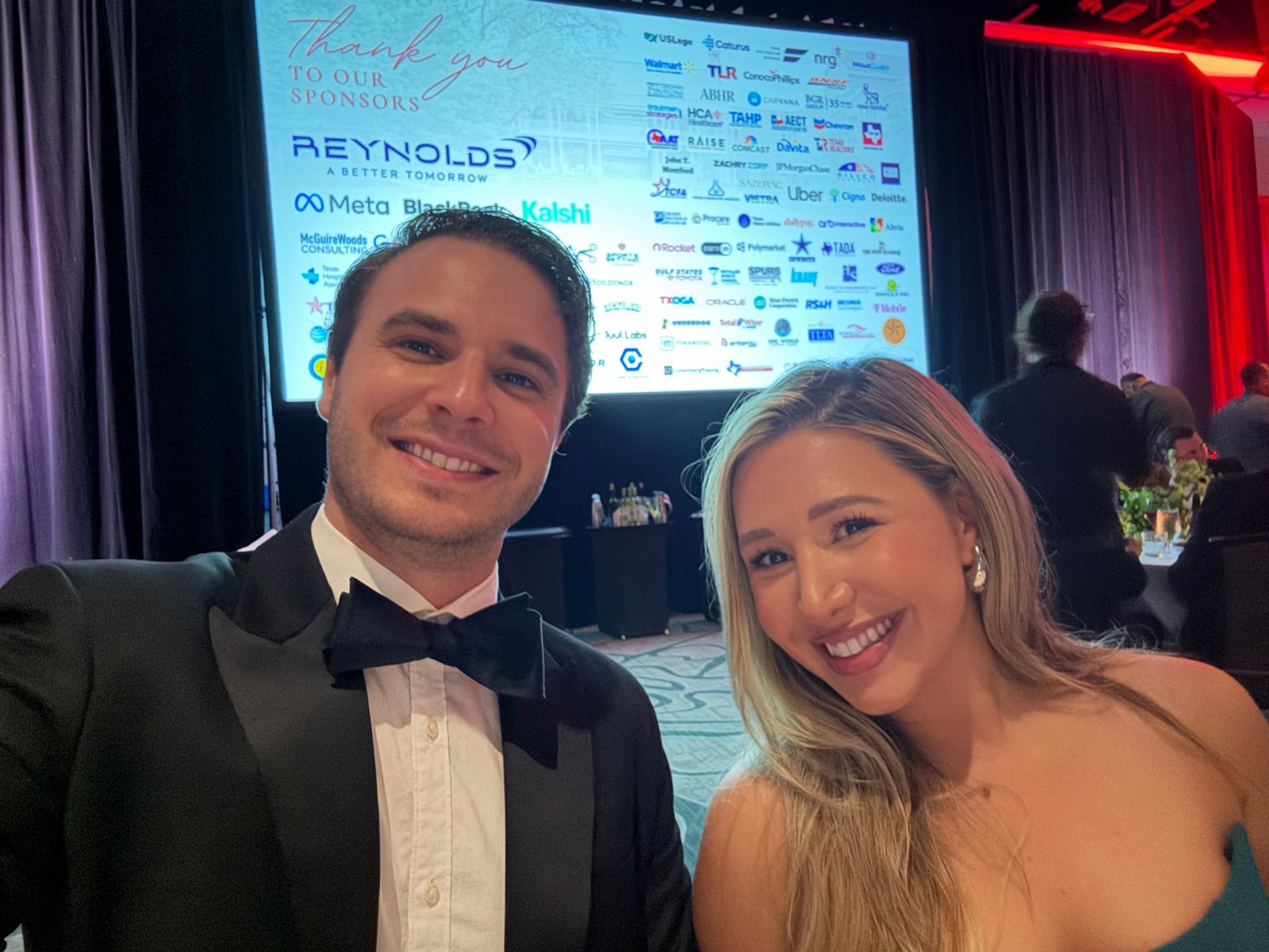 Laura Davis and a guest posing in front of the sponsor thank-you screen at the Senate Republican Caucus Gala