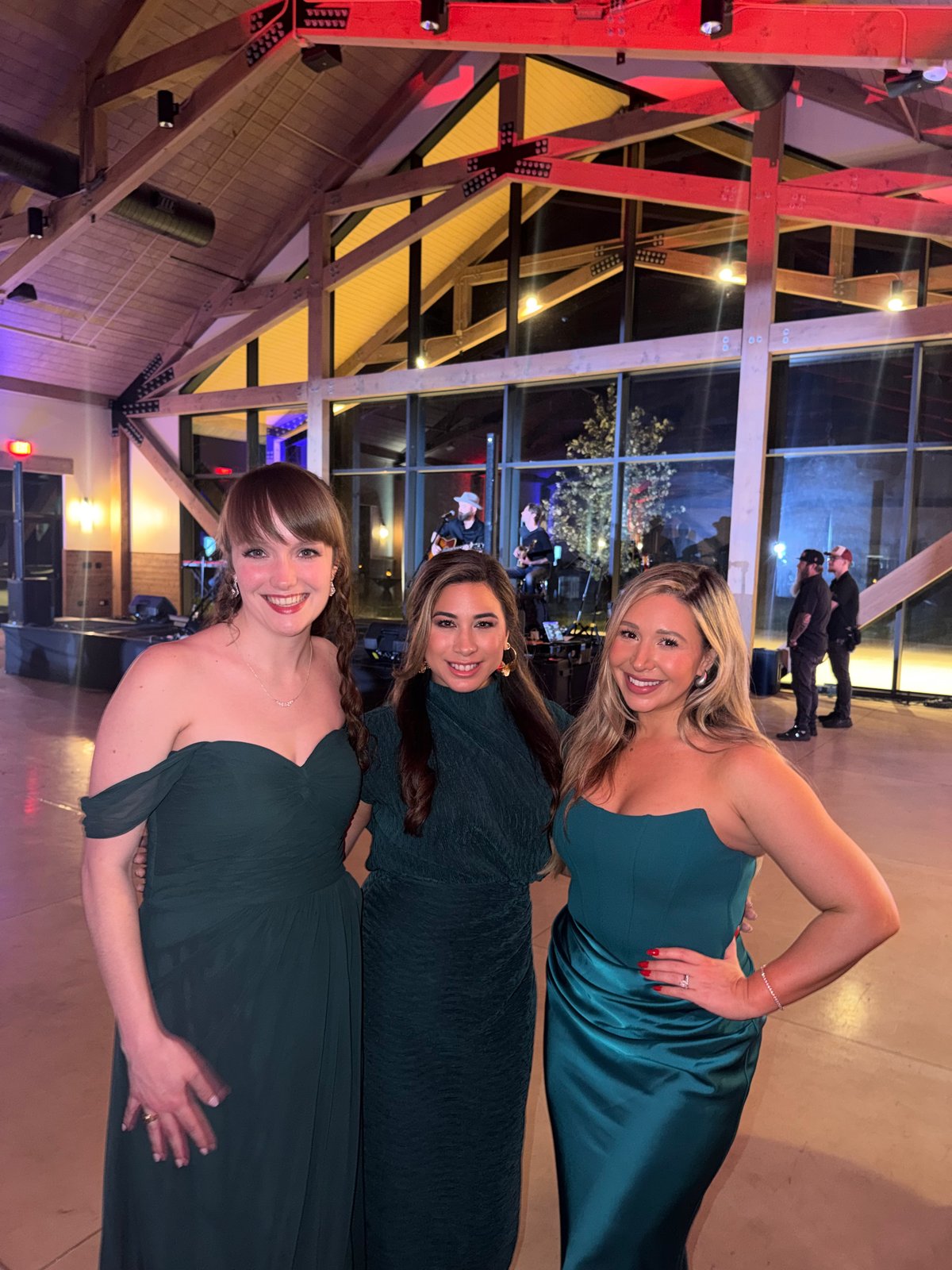 Three guests posing together with the live band performing in the background at the Senate Republican Caucus Gala