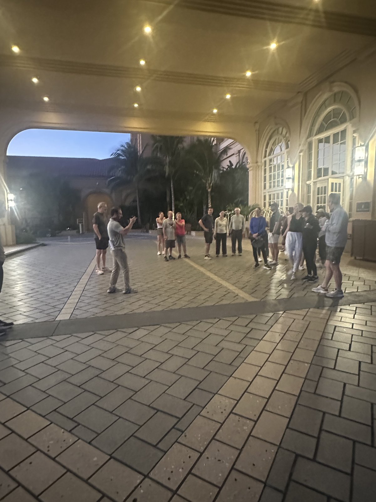 A group of SGAC attendees chatting under the hotel portico before the fun run