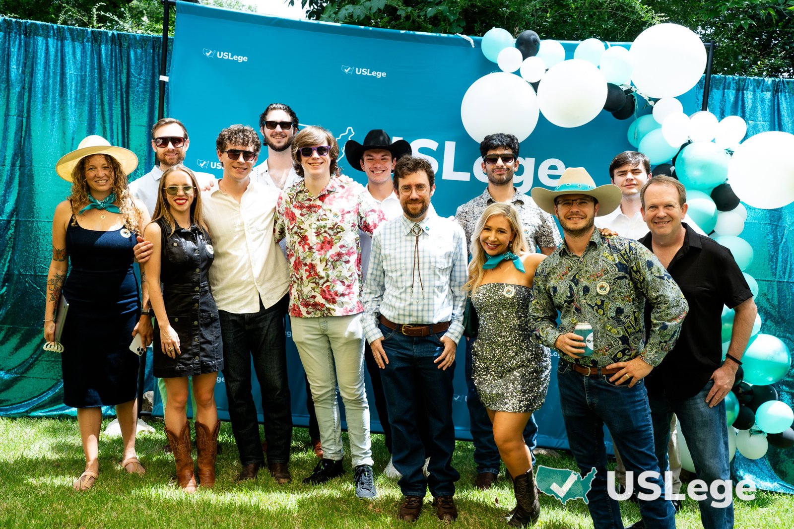 A large group of USLege team members and guests posing together in front of the USLege step-and-repeat backdrop