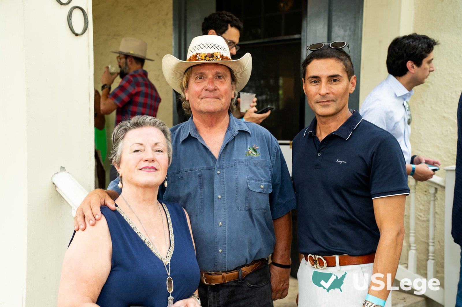 Three guests posing together on the porch at the Sine Die Celebration