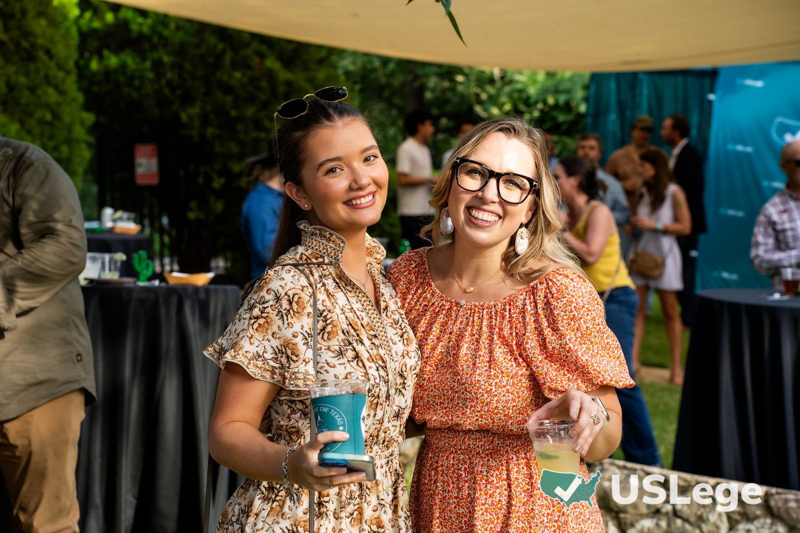 Two guests smiling together and holding drinks at the Sine Die Celebration